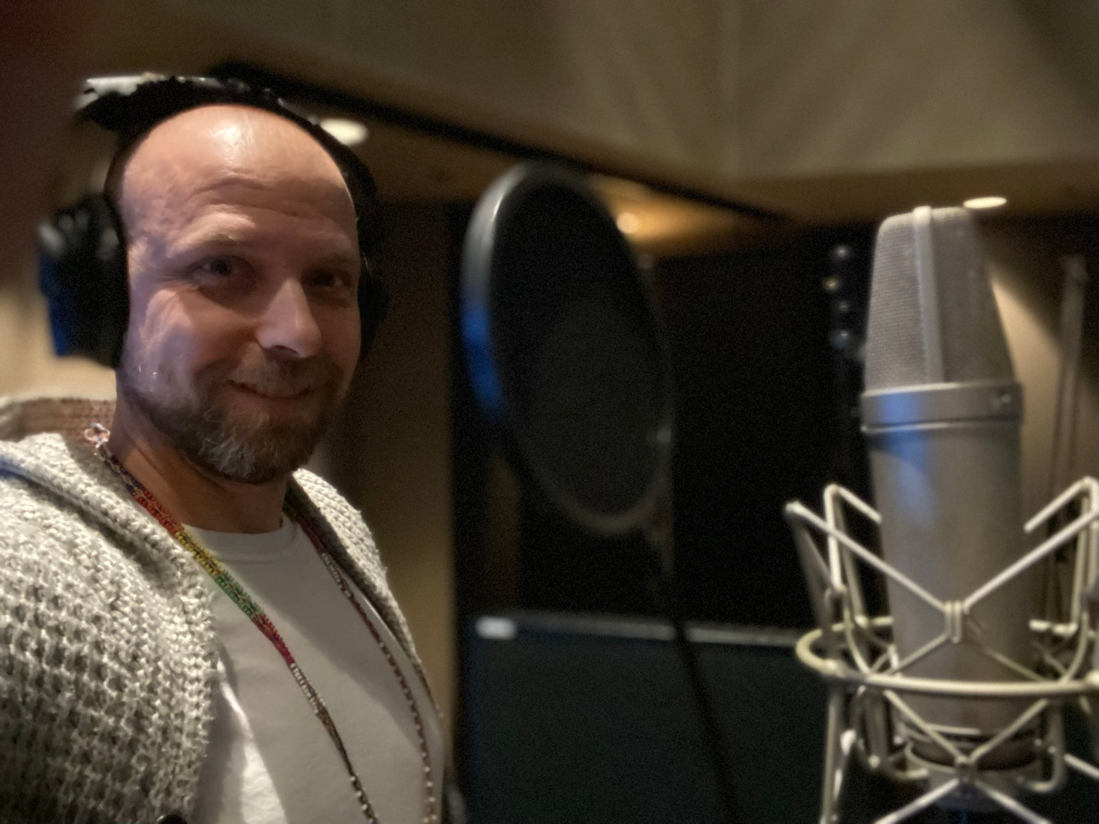 Brad Floyd at the microphone in the studio, headphones on, half smiling